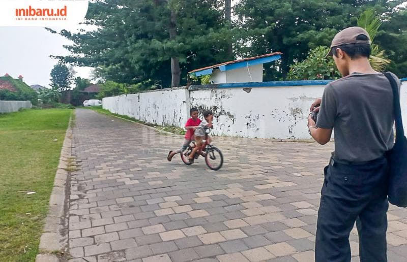 Seorang anggota Komunitas Blusuk.an memotret anak kecil yang sedang menaiki sepeda. (Inibaru.id/ Fitroh Nurikhsan)