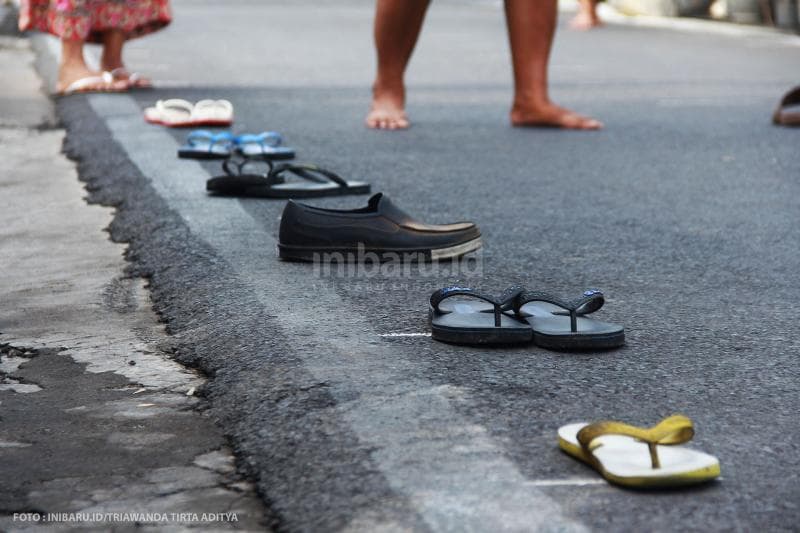 Penerima sedekah harus meletakkan sandal mereka sebagai bukti antrean.<br>