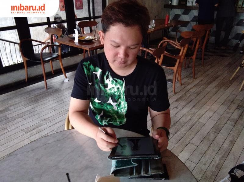 Niki Hutomo tengah membuat kreasi busana di layar pintarnya. (Inibaru.id/ Isma Swastiningrum)<br>