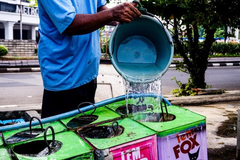 Memenuhi kaleng-kaleng dengan air.<br>