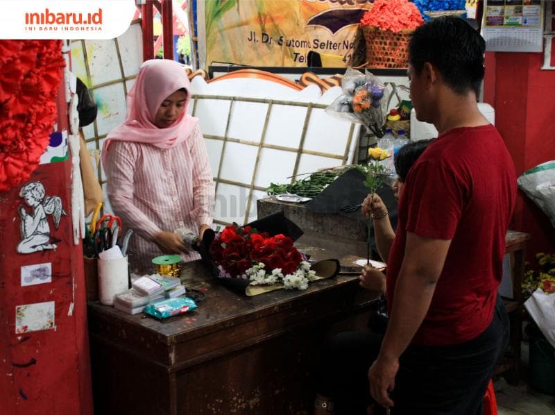 Daria sedang melayani pengunjung yang minta rangkaian bunga. (Inibaru.id/ Audrian F)<br>