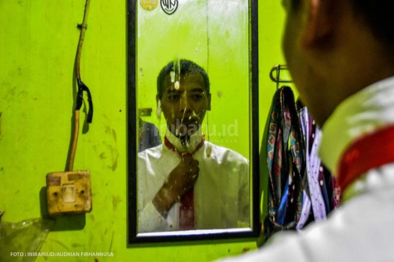 Bercermin untuk merapikan dasi.