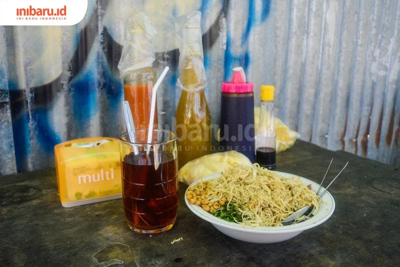 Penampakan setengah porsi bubur ayam Mang Dede bersama kerupuk, sambal, dan kuah dalam botol tak lupa dengan teh hangat untuk minumya. (Inibaru.id/ Kharisma Ghana Tawakal)