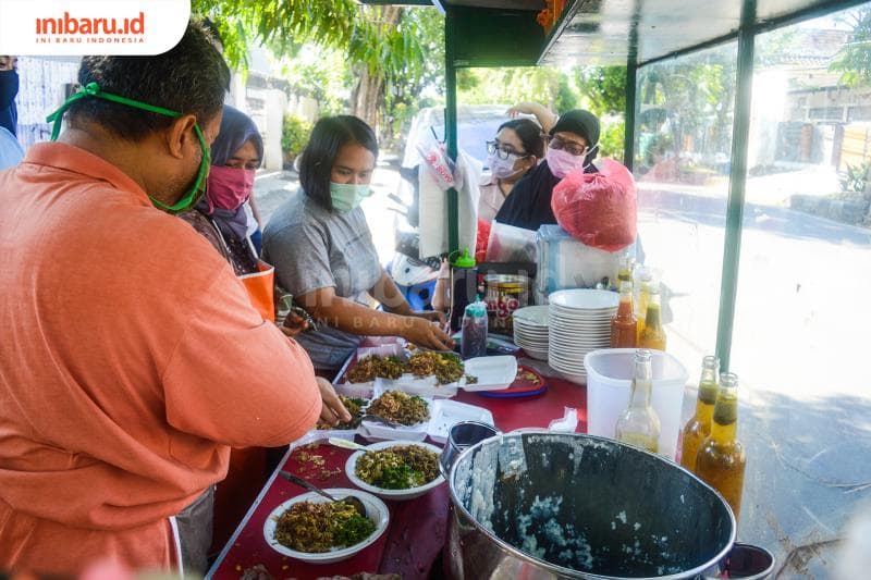 Mang Dede, sang istri, dan anaknya sedang meracik bubur ayam pesanan pelanggan.&nbsp;(Inibaru.id/ Kharisma Ghana Tawakal)