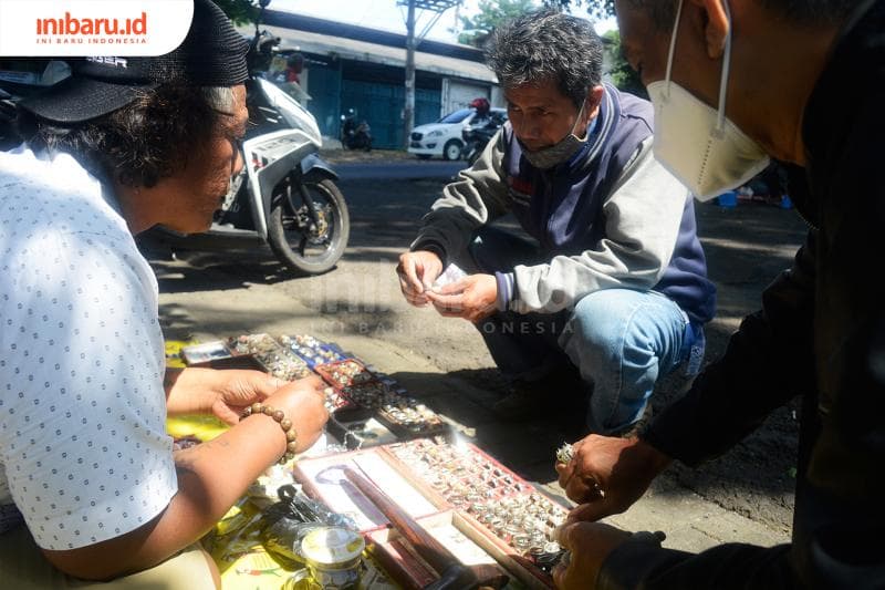 Mbah Min (kiri) sedang melayani pelanggan akik yang datang ke lapaknya.&nbsp;(Inibaru.id/ Kharisma Ghana Tawakal)