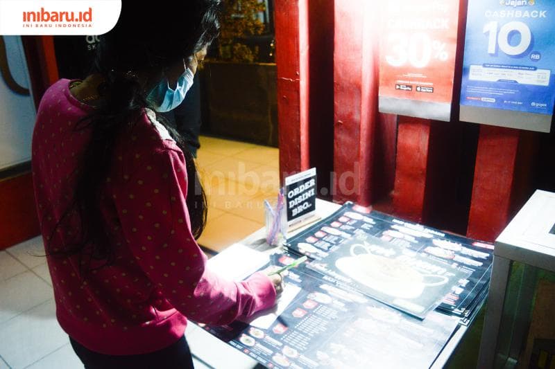 Salah seorang pengunjung yang datang dan menuliskan pesanan di dekat pintu masuk Nasi Goreng Padang Bangjo Semarang. (Inibaru.id/ Kharisma Ghana Tawakal)