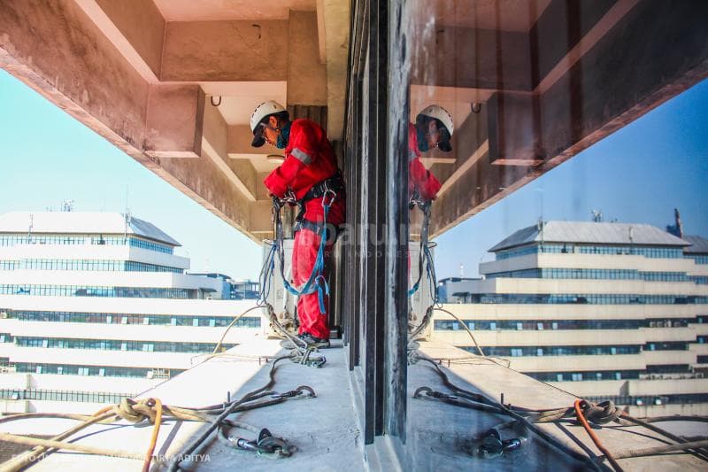 Inilah Aji, salah satu rope access yang sedang bersiap memasang bendera di dinding gedung berlantai tujuh di Kota Semarang.<br>