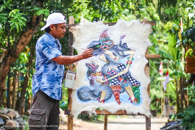 Aktivitas Kumoro saat melukis di depan rumahnya.
