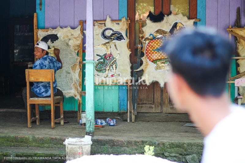 Warga desa melihat aktivitas melukis Kumoro dari kejauhan.