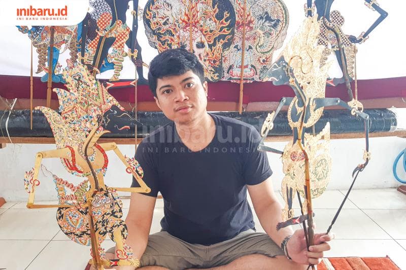 Ekky dengan dua wayang buatannya di tangan. (Inibaru.id/Kharisma Ghana Tawakal)