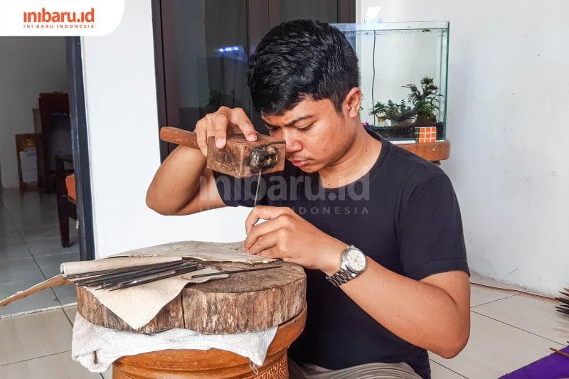 Ekky sedang menatah kulit kerbau yang akan dijadikan wayang. (Inibaru.id/ Kharisma Ghana Tawakal)