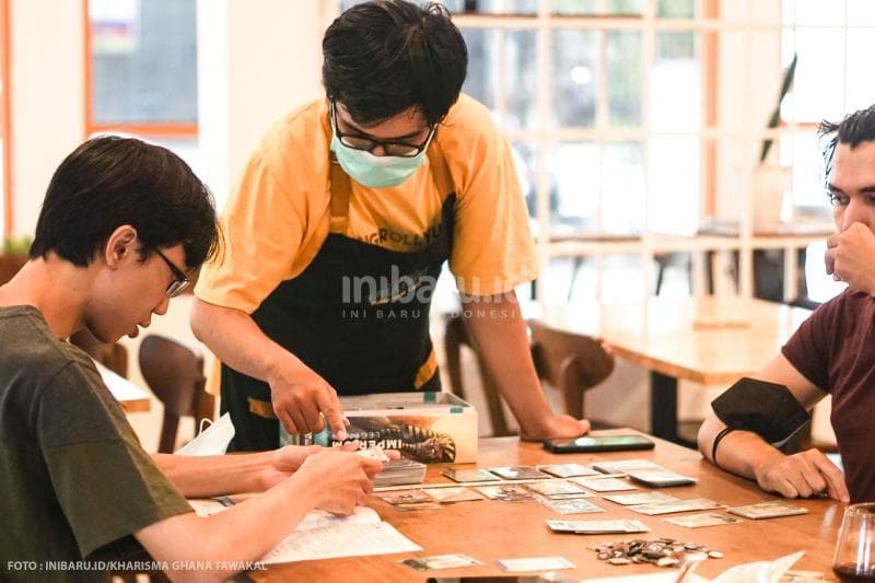 Game Master menjelaskan cara kerja dan konsep permainan kepada pelanggan cafe.