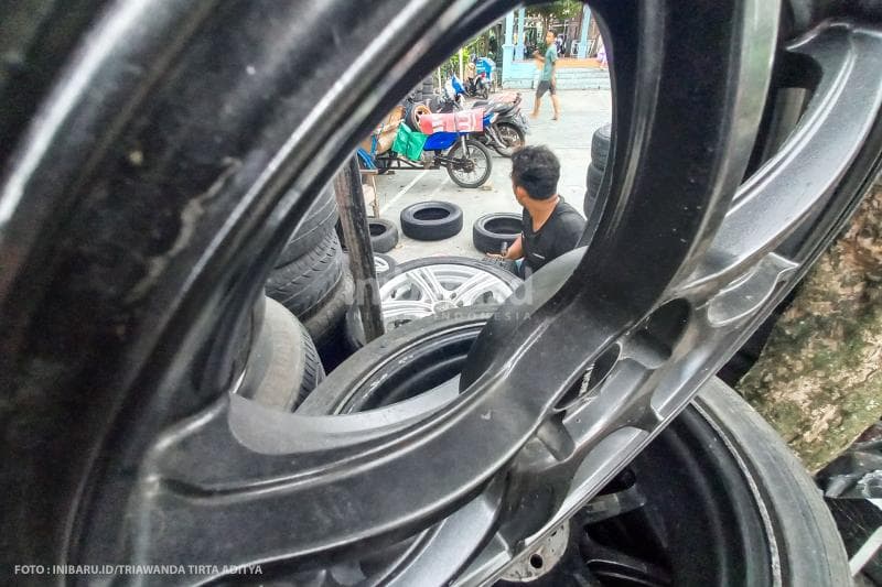 Pedagang mempersiapkan ban yang akan dibeli.