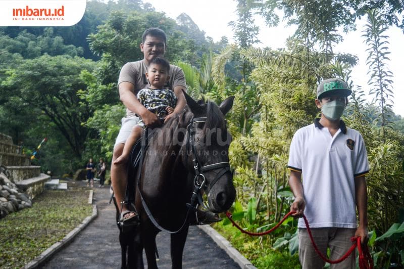 Salah seorang pengunjung yang berkuda bersama anak mengelilingi Santosa Park.&nbsp; (Inibaru.id/ Kharisma Ghana Tawakal)