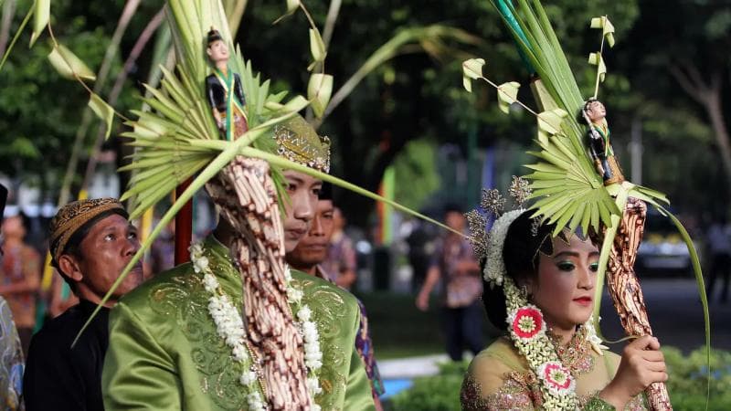 Mempelai pria dan wanita membawa tebu untuk dinikahkan sebagai simbolik dalam upacara Cembengan. (Liputan6)