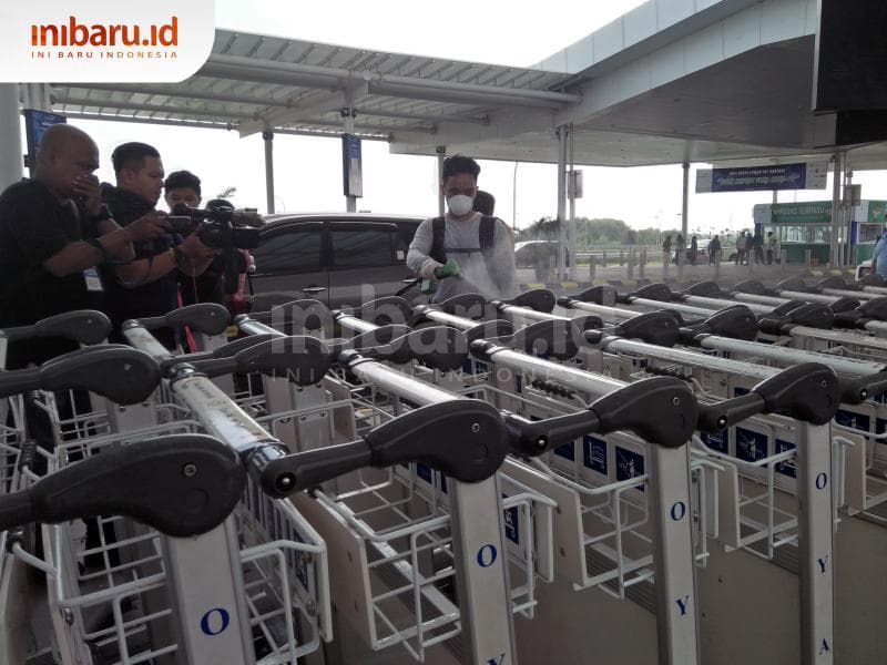 Petugas melakukan penyemprotan di troli-troli bandara Ahmad Yani Semarang. (Inibaru.id/ Issahani)<br>