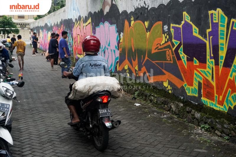 Warga melintas di tengah aktivitas menggambar grafiti. (Inibaru.id/ Audrian F)<br>