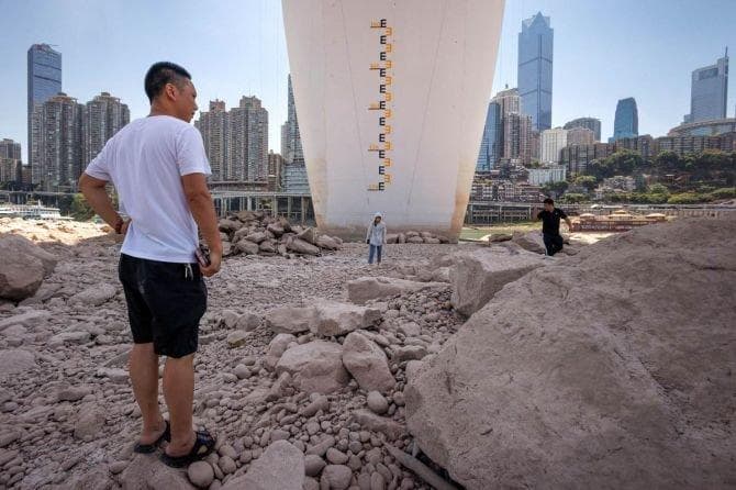 Warga berjalan di dasar salah satu sungai di Tiongkok, dengan penanda kedalaman air di sebuah tiang di latar belakang. (Twitter/unsc1325)