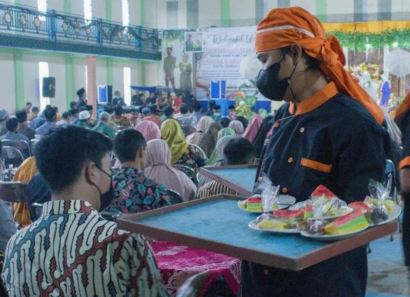 Pramusaji yang sedangn menghantarkan 'piring terbang' kepada tamu undangan. (Instagram/R.A Catering Service Solo)