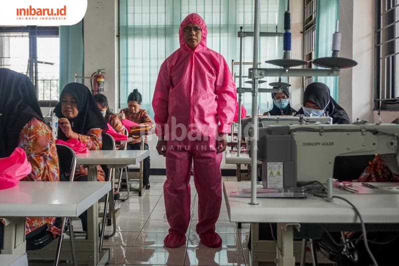 Salah seorang penjahit APD sedang mencoba pakaian APD. (Inibaru.id/ Audrian F)<br>