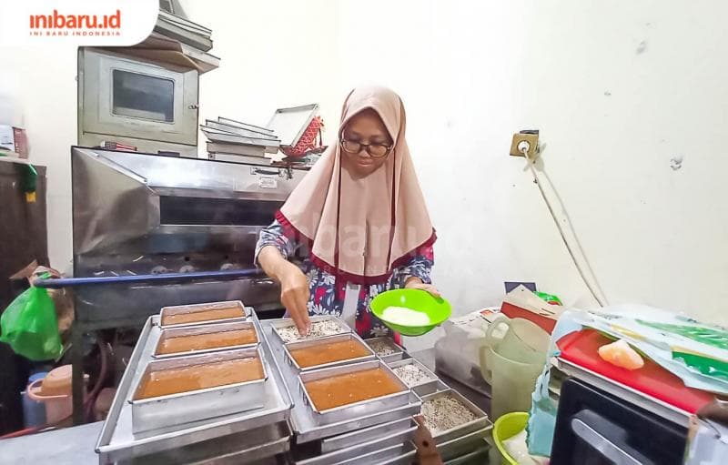 Pegawai di Omah Ganjel Rel sedang menaburkan wijen di atas adonan basah roti ganjel rel. (Inibaru.id/ Fitroh Nurikhsan)