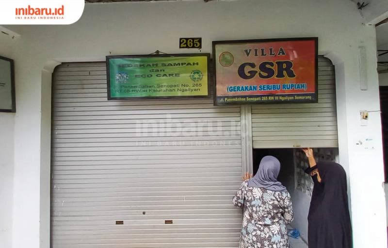 Ketua GSR Misbah Zulfa Elisabeth bersama seorang warga tengah membuka gudang penyimpan barang-barang bekas kepunyaan mereka. (Inibaru.id/ Fitroh Nurikhsan)