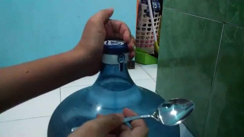 Membuka tutup galon dengan memakai sendok. (YouTube/Toko Jelek Surabaya)