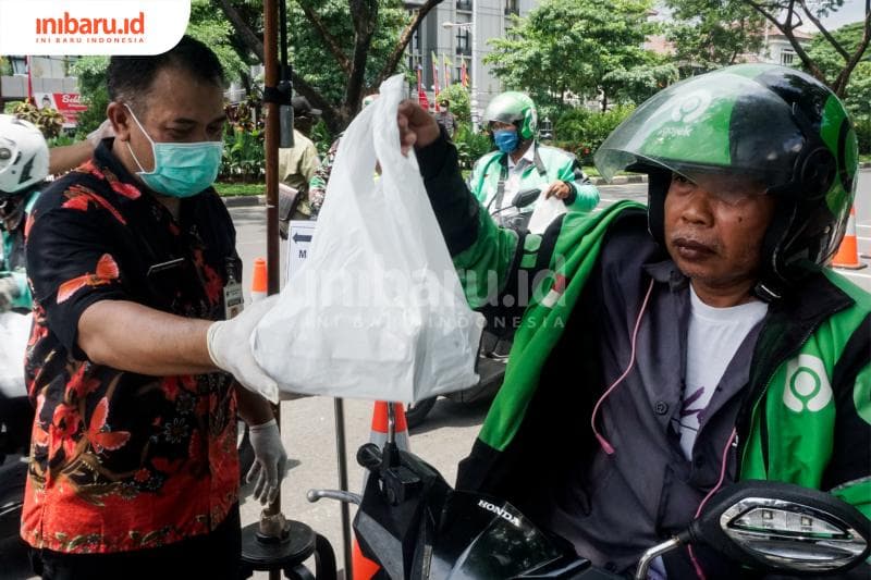 Seorang pengendara ojek daring menerima nasi gratis dari Pemprov Jawa Tengah. (Inibaru.id/ Audrian F)<br>