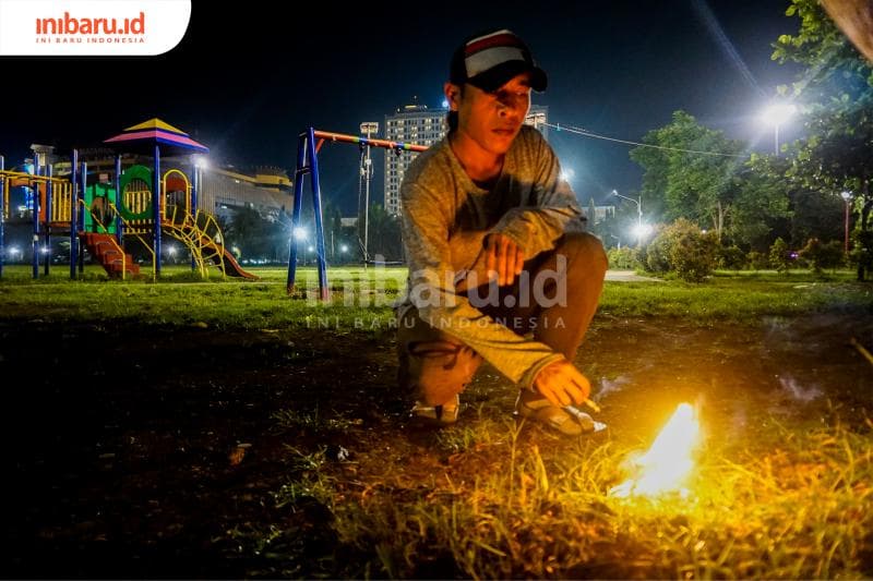 Danu tengah membuat api unggun di tengah sunyinya Simpang Lima. (Inibaru.id/ Audrian F)<br>