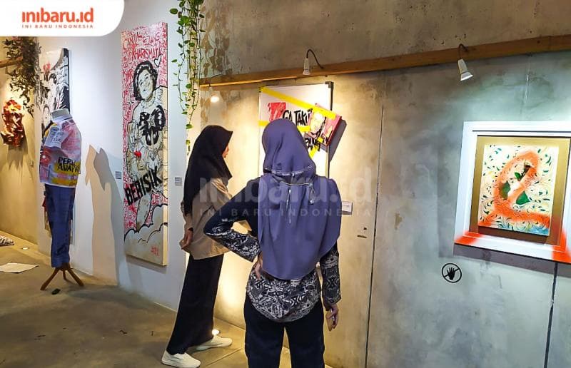 Pengunjung pameran tengah mengamati karya berjudul Anak Polah Bapa Kepradhah.&nbsp;(Inibaru.id/ Rizki Arganingsih)