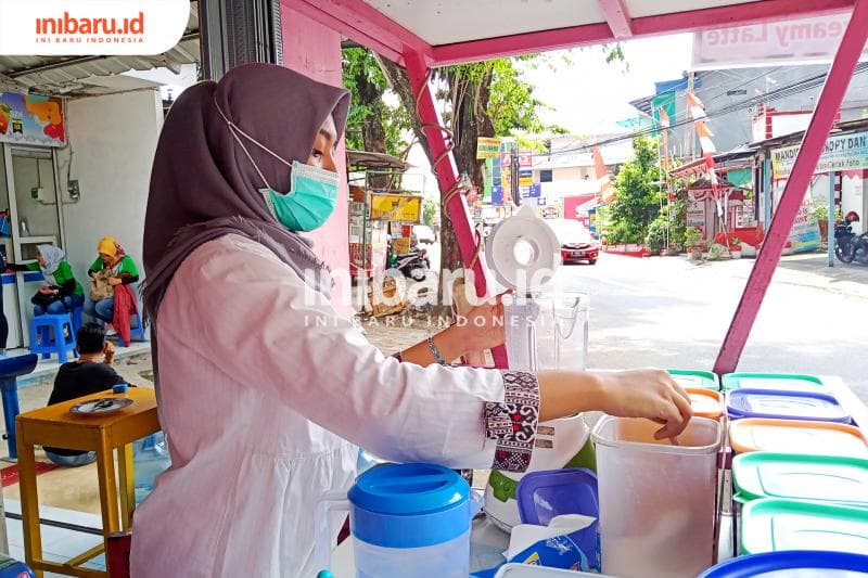 Chacha memakai masker dan hand sanitizer saat berjualan. (Inibaru.id/ Zulfa Anisah)