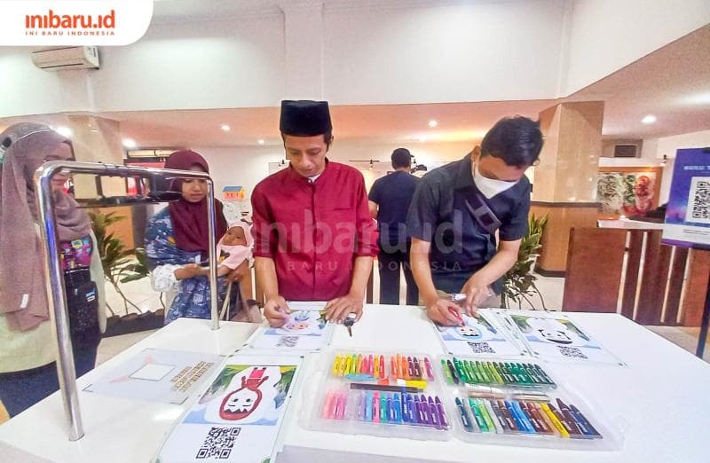 Dua orang pengunjung sedang mengikuti kuis menggambar yang diadakan di museum penerangan. (Inibaru.id/ Fitroh Nurikhsan)