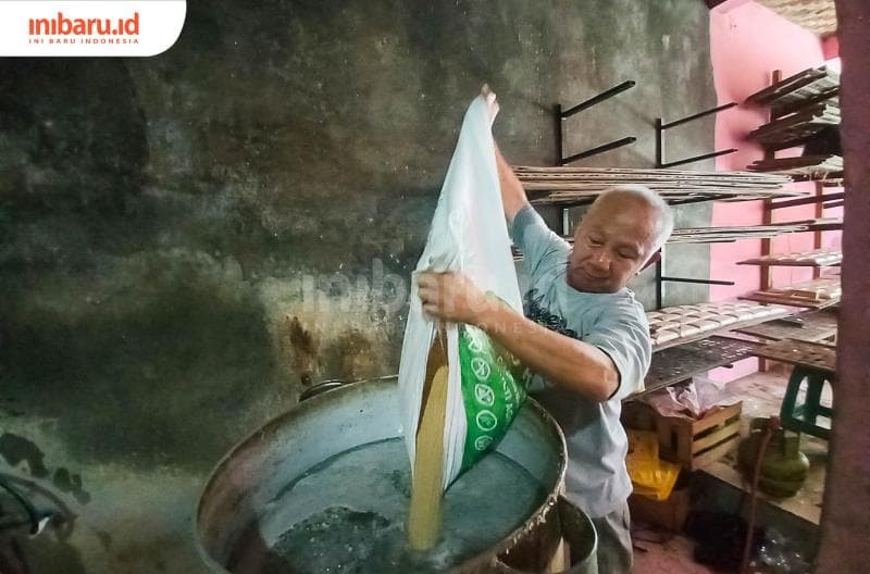 Jumadi sedang menuangkan kedelai untuk proses perebusan. (Inibaru.id/ Fitroh Nurikhsan)