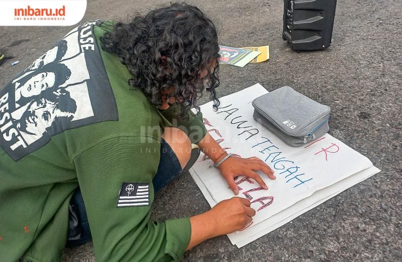 Seorang anggota Aksi Kamisan Semarang sedang membuat tulisan 'Jawa Tengah Tenggelam'. (Inibaru.id/ Fitroh Nurikhsan)