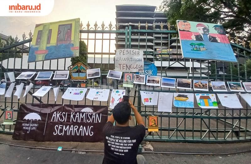 Seseorang tengah memotret pernak-pernik Aksi Kamisan Semarang yang tertempel rapi di gerbang gubernuran. (Inibaru.id/ Fitroh Nurikhsan)