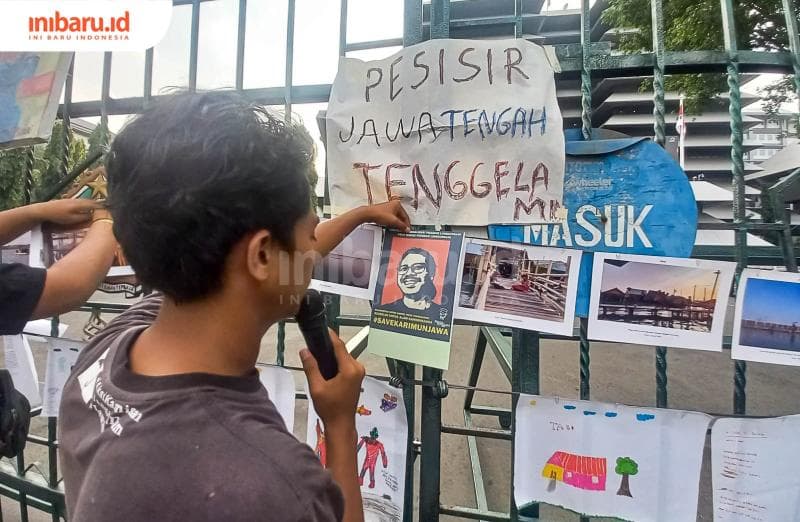 Seorang orator Aksi Kamisan Semarang sedang menunjukkan karya-karya yang ditempel di pagar besi. (Inibaru.id/ Fitroh Nurikhsan)