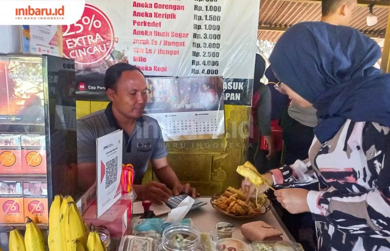 Sosok Zainal Arifin tengah menghitung jajanan yang diambil pembeli. (Inibaru.id/ Fitroh Nurikhsan)