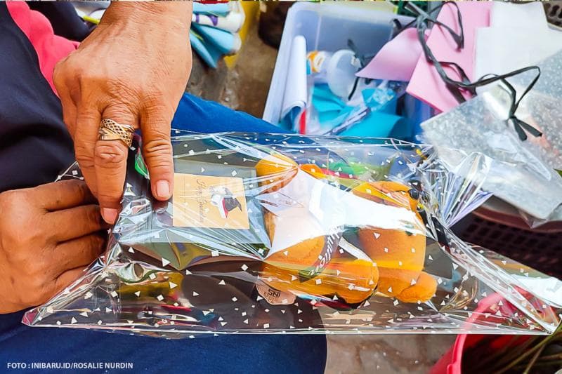Proses pembungkusan buket boneka ke dalam plastik.