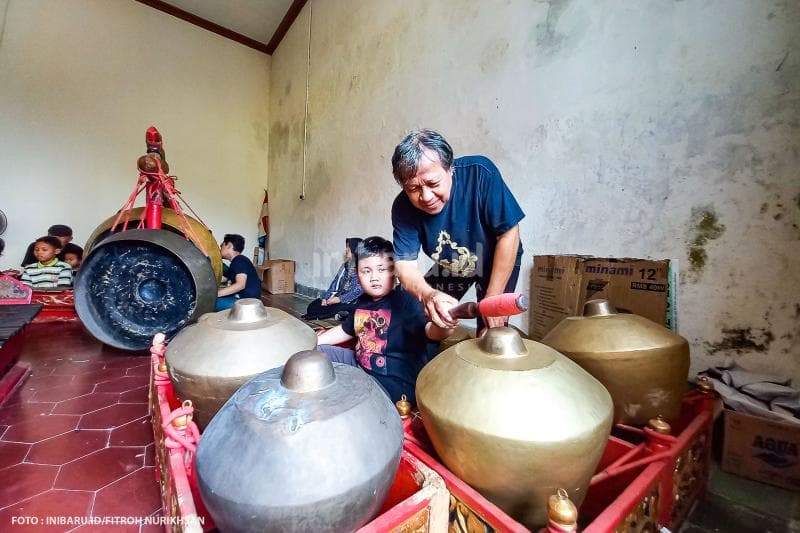 Seorang pembina memberikan contoh cara menabuh kenong dengan baik.