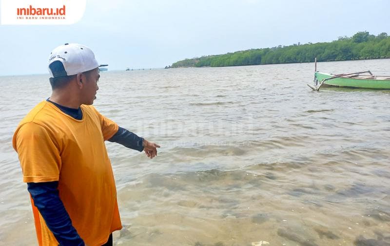 Seorang warga Karimunjawa menunjukkan lumut-lumut hitam yang diduga berasal dari limbah tambak udang. (Inibaru.id/ Fitroh Nurikhsan)