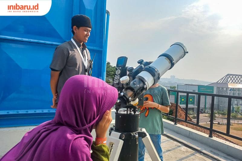 Seorang pengunjung sedang mengamati objek matahari menggunakan teleskop yang disediakan Planetarium UIN Walisongo. (Inibaru.id/ Fitroh Nurikhsan)