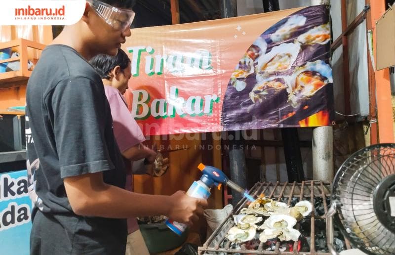 Proses pembakaran tiram bakar dengan menggunakan torcher dan arang. Setelah dimasak selama beberapa menit, tiram diolesi dengan saus racikan.&nbsp;(Inibaru.id/ Ayu Sasmita)