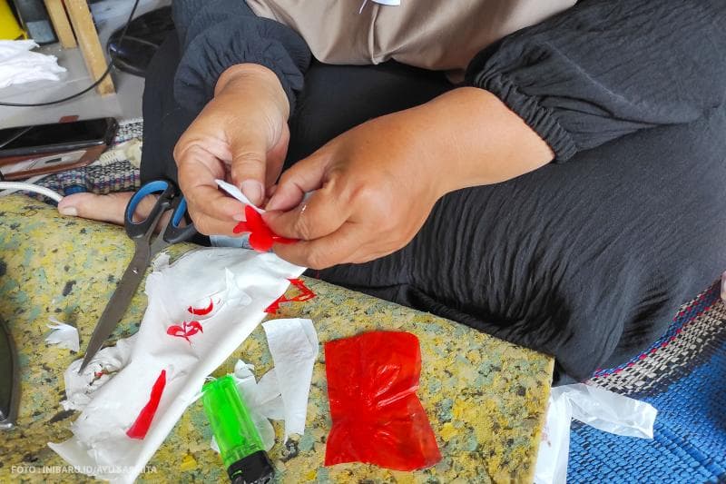 Plastik yang sudah disetrika siap dirangkai menjadi bunga untuk membuat gaun acara fashion show.&nbsp;