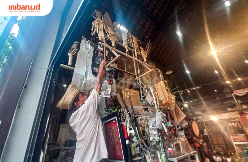 Ahmad Rofiq sedang mengambil wayang suket yang menggelantung di kiosnya. (Inibaru.id/ Fitroh Nurikhsan)
