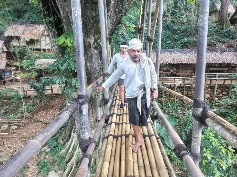 Tokoh Badui Dalam, Karmain, saat melintas di salah satu jembatan kayu. (Inibaru.id/ Fitroh Nurikhsan)
