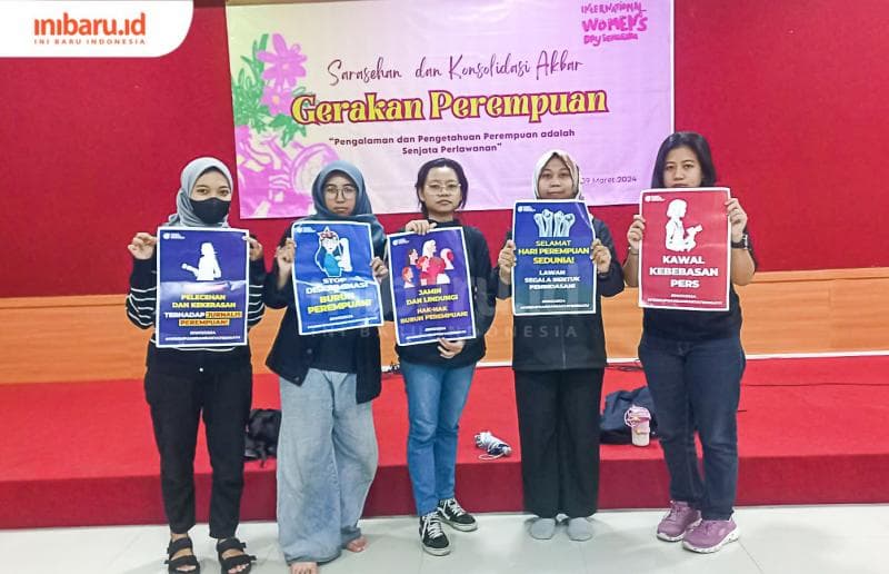 Beberapa perempuan jurnalis di Kota Semarang membentangkan poster saat acara IWD 2024. (Inibaru.id/ Fitroh Nurikhsan)