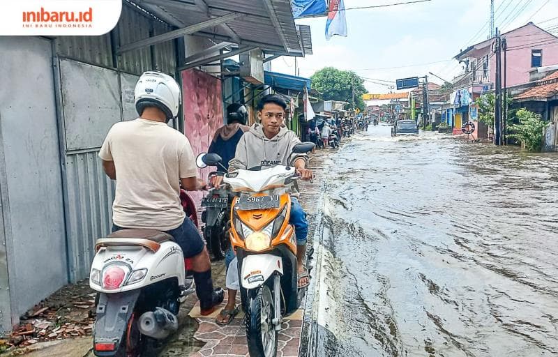 Pengendara motor melewati trotoar demi menghindari genangan banjir. (Inibaru.id/ Fitroh Nurikhsan)