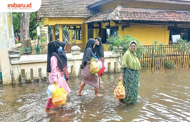 Para warga saat melewati genangan banjir setelah mengikuti pengajian. (Inibaru.id/ Fitroh Nurikhsan)