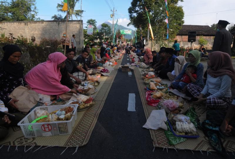 Warga makan bersama sebelum arak-arakan Lebaran Hewan digelar. (Kompas/Kristianto Purnomo)