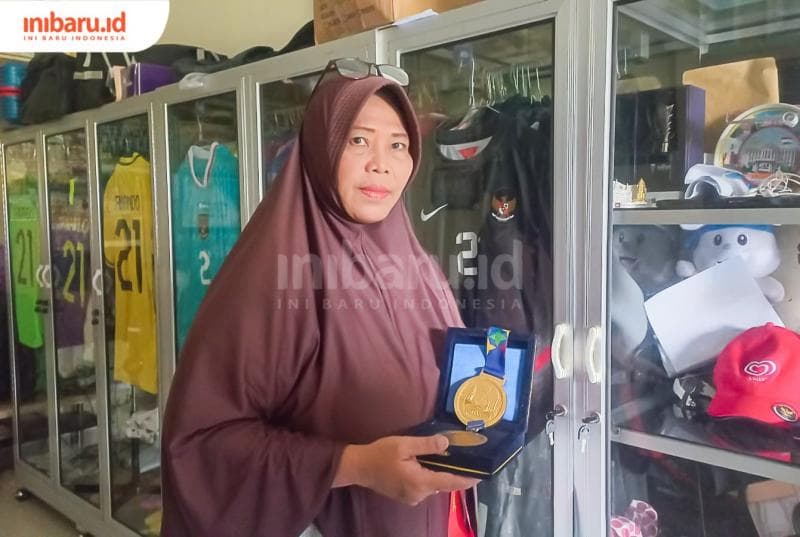 Erna Yuli Lestari memperlihatkan salah satu medali yang diraih anaknya Ernando Ari Sutaryadi. (Inibaru.id/ Fitroh Nurikhsan)